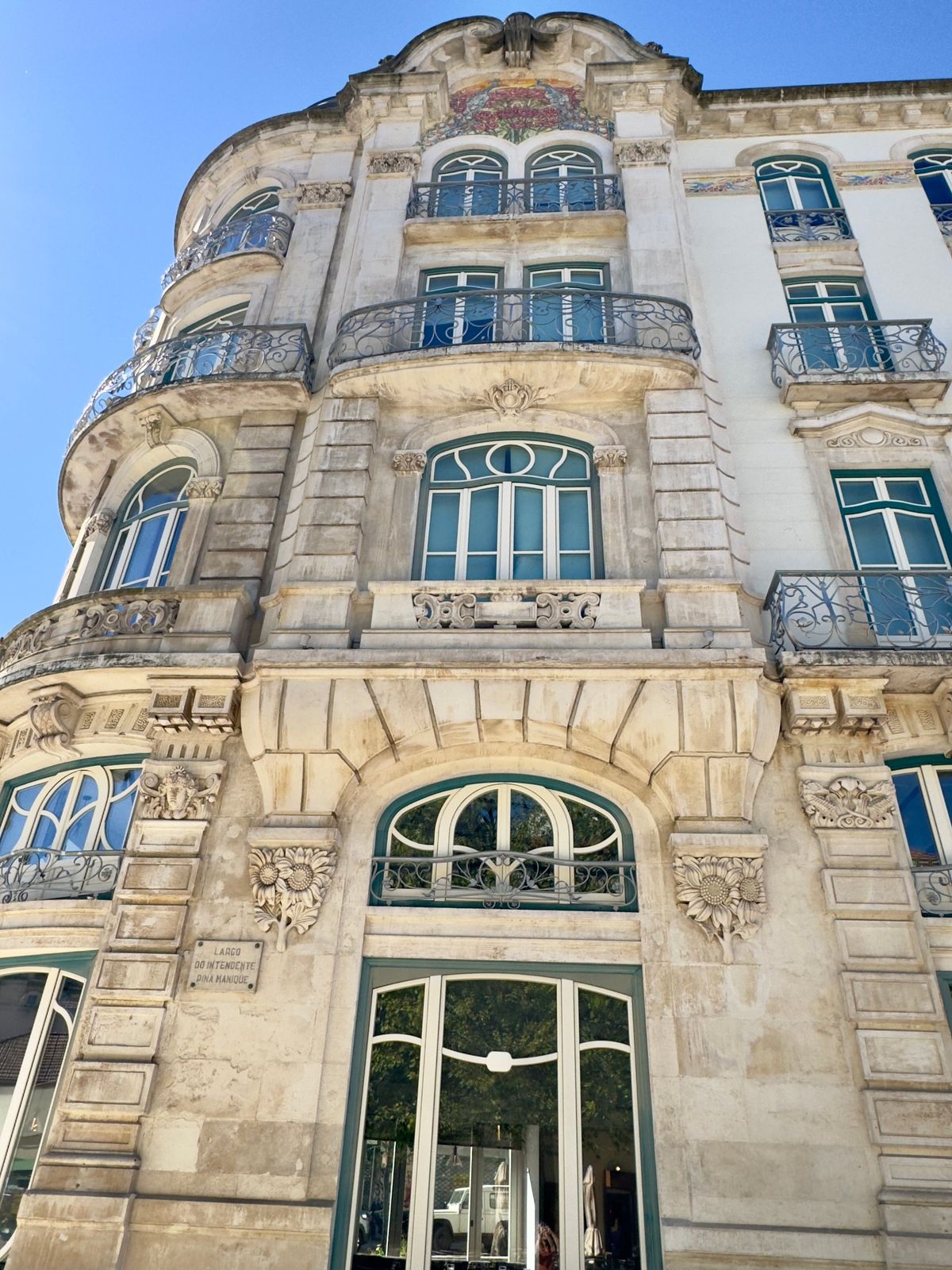 An ornate stone Art Nouveau building with curved iron balconies and carved sunflowers